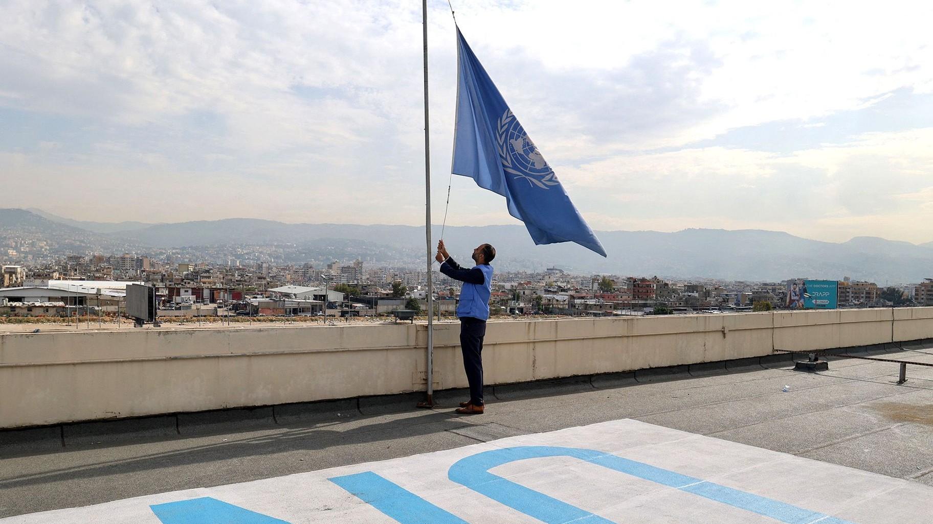 An UNRWA employee lowers the UN flag at the organization’s offices in the Lebanese capital Beirut on Nov. 13, as the flags flew at half-staff at UN compounds across the globe as staff observed a minute's silence for colleagues killed in Gaza. (Anwar Amro / AFP / Getty Images)